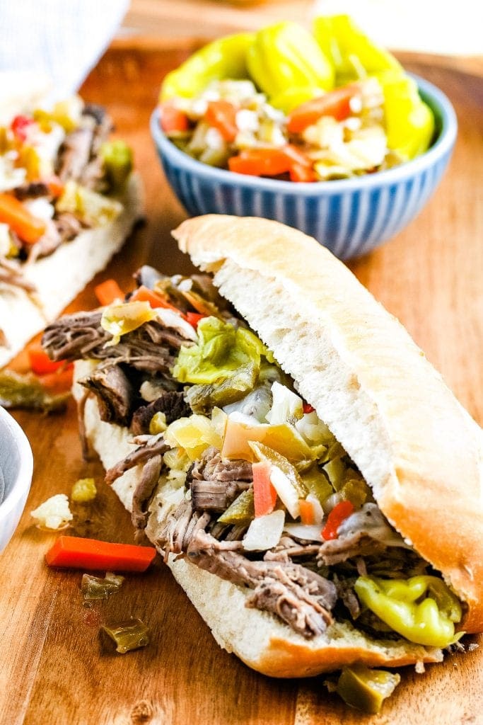 Wood cutting board with two hoagies filled with Italian Beef