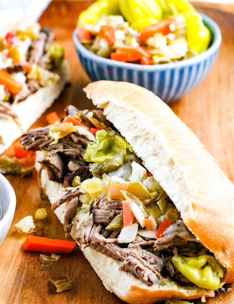 Wood cutting board with two hoagies filled with Italian Beef