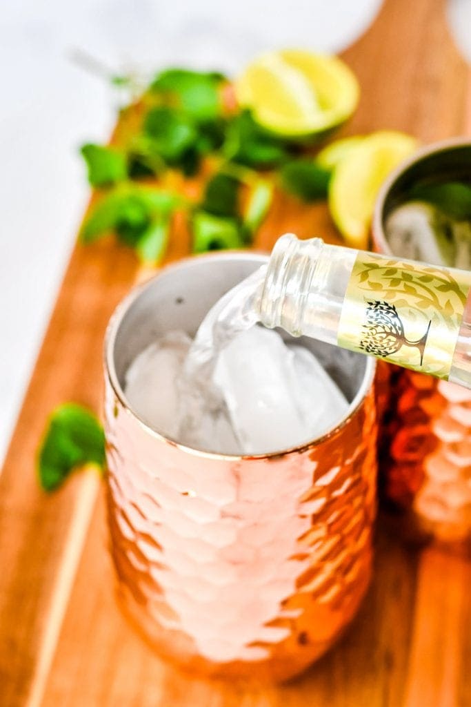 Pouring ginger beer into a copper mug.