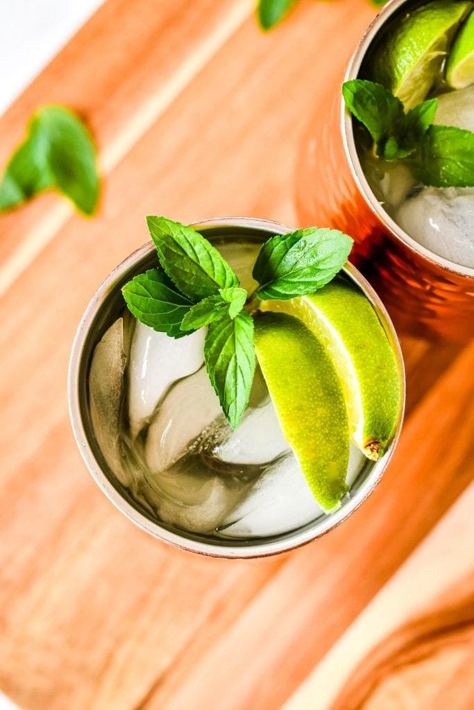 Overhead image looking into copper mug full of moscow mule that's garnished with lime wedges and mint sprig.