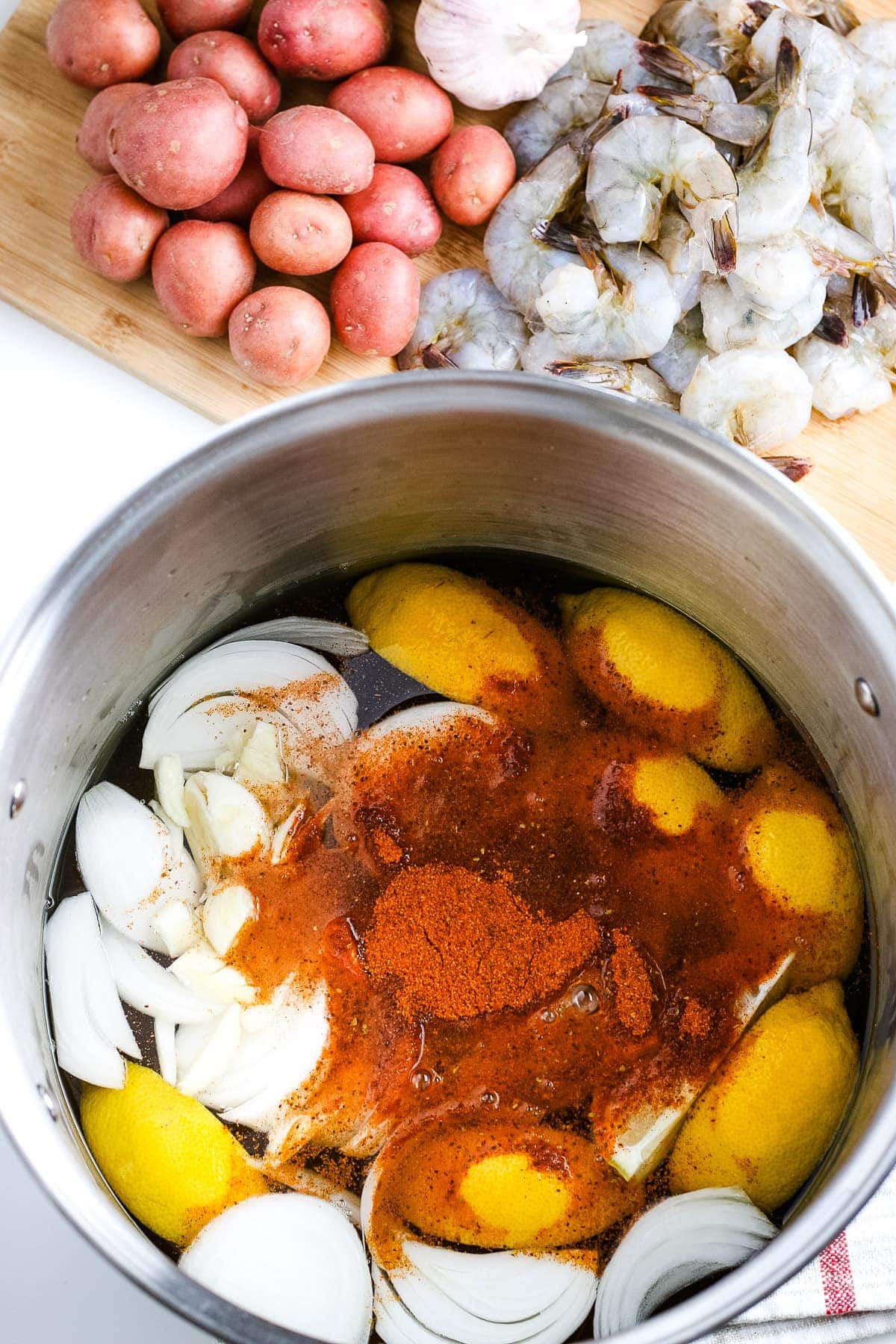 Water with sliced lemons, onions and seasonings for shrimp boil