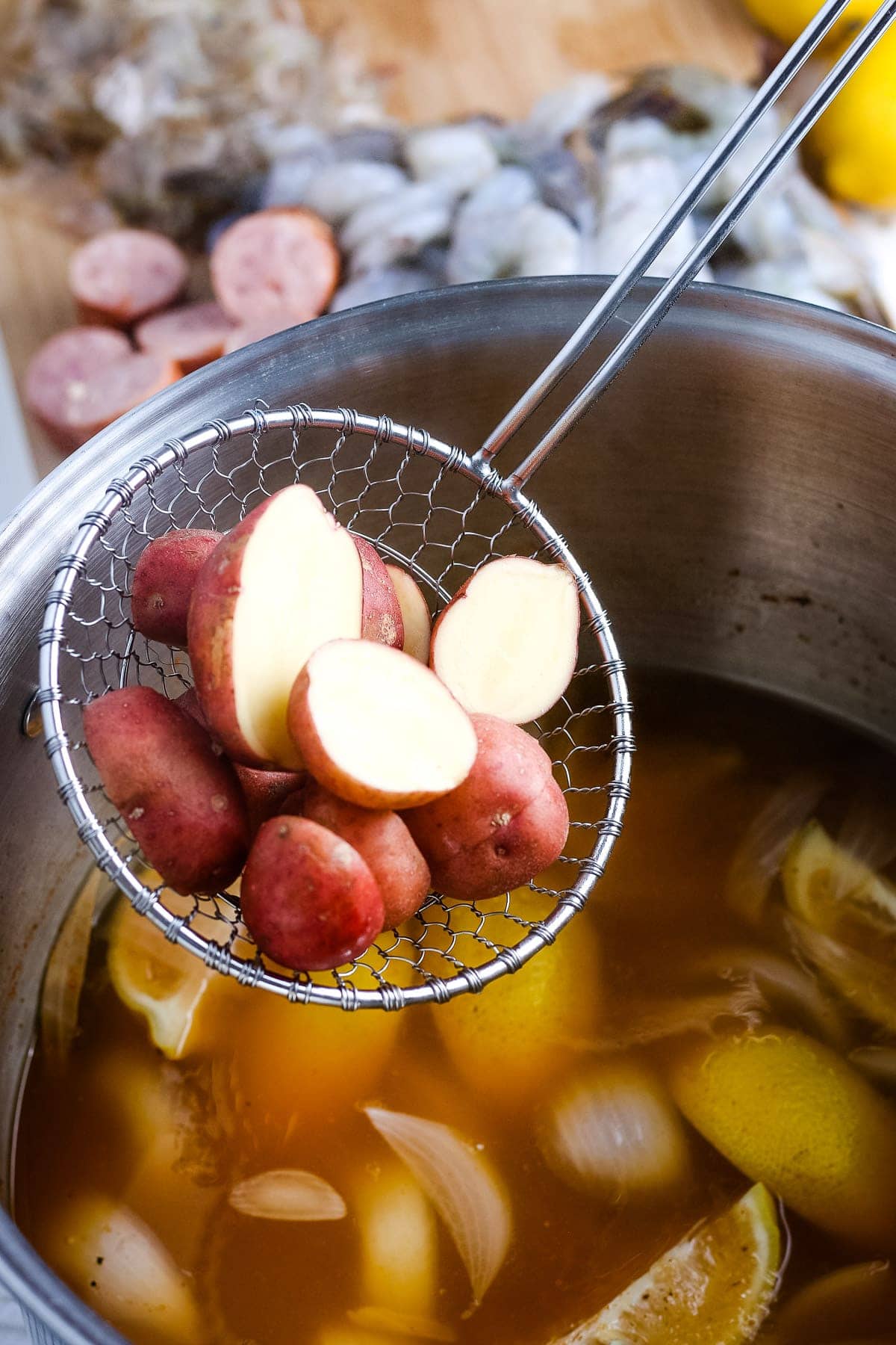 Ladle holding sliced baby red potatoes before putting it into shrimp boil.