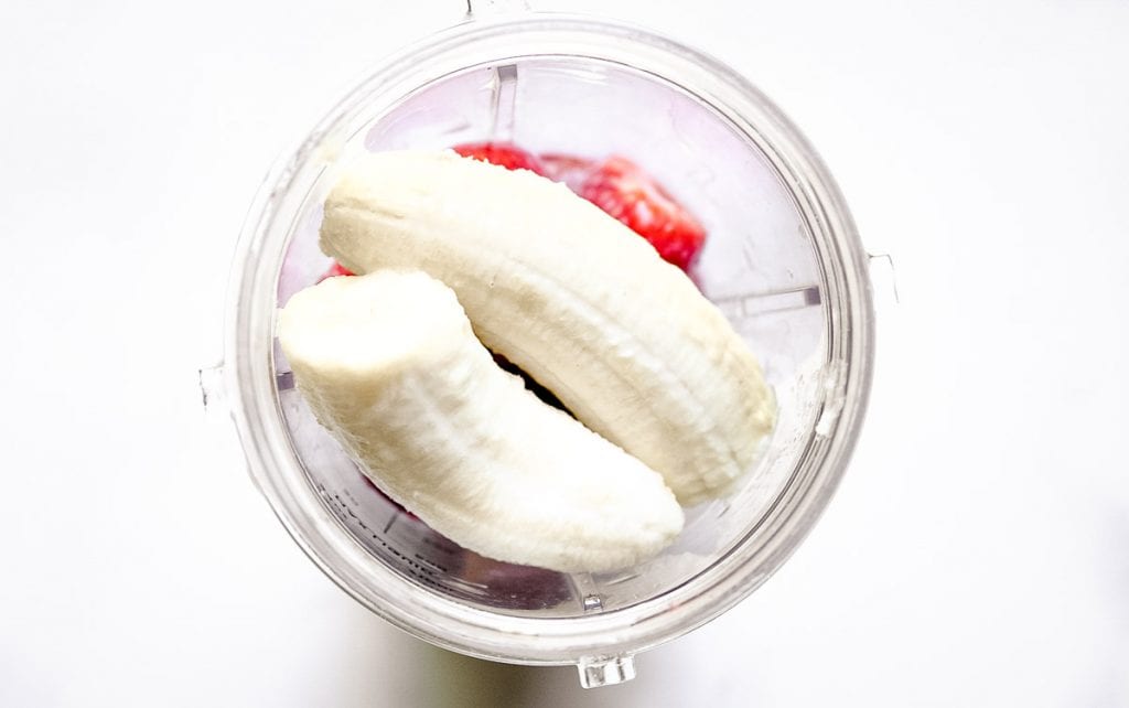 Overhead image of bananas and strawberries in blender