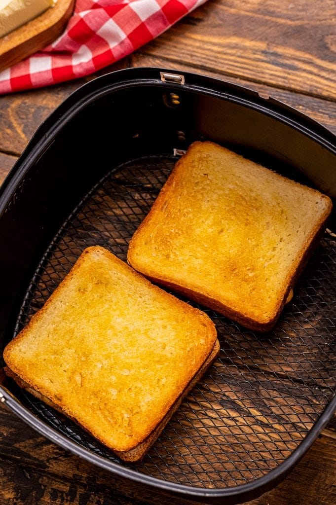 Two grilled cheese sandwiches in air fryer after cooking.