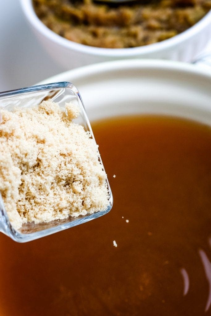 Brown Sugar being added to apple cider in stockpot.