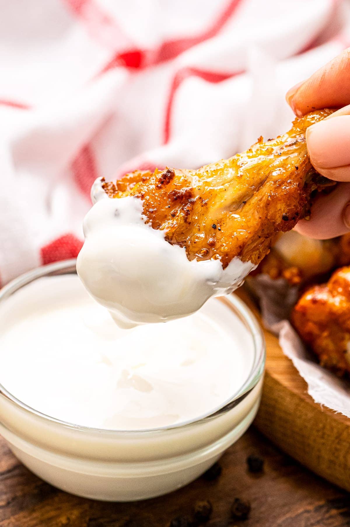 Hand holding chicken wing that is dipped in ranch