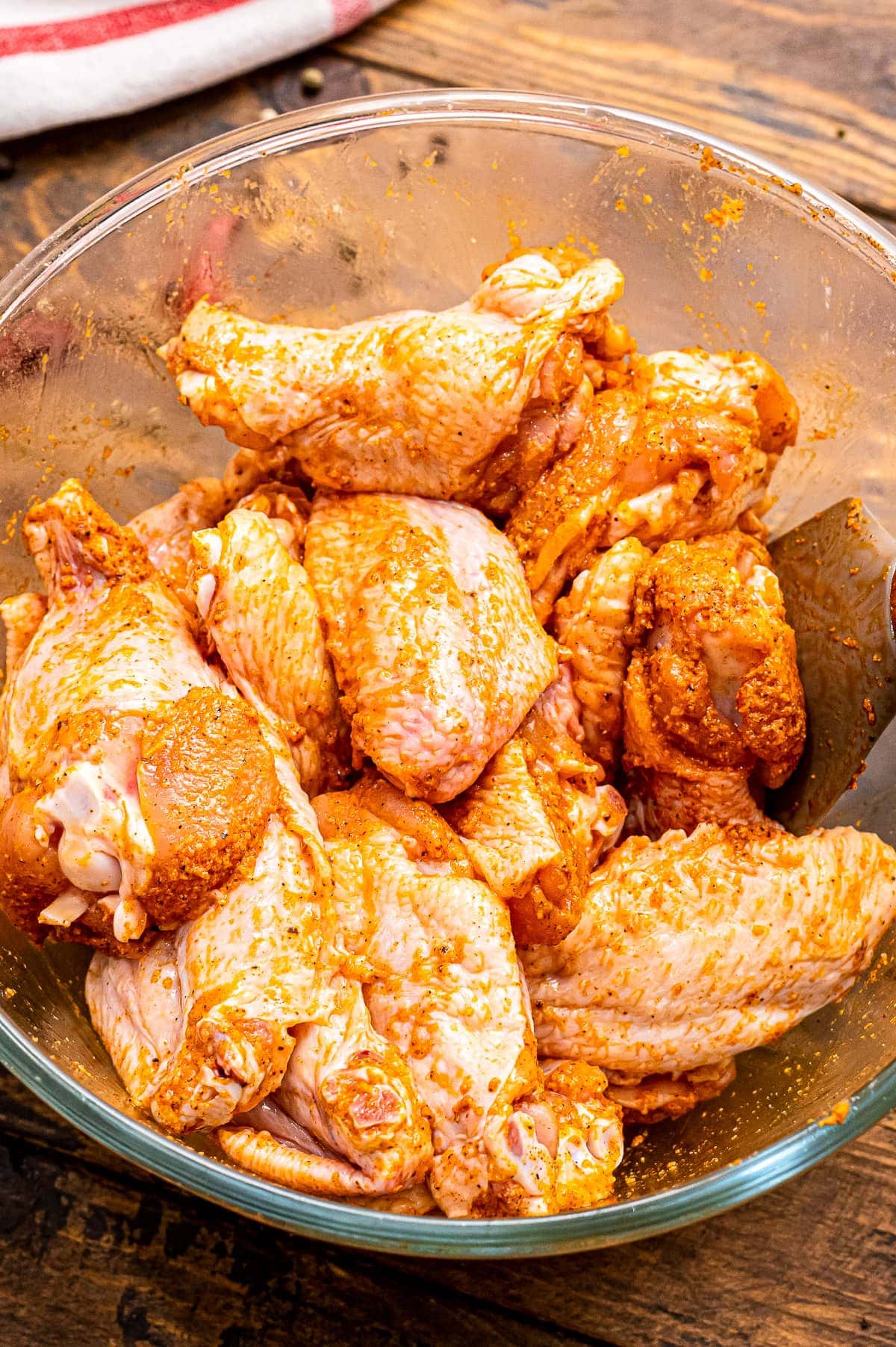 Glass bowl with wings that are seasoned with a rub mixture.