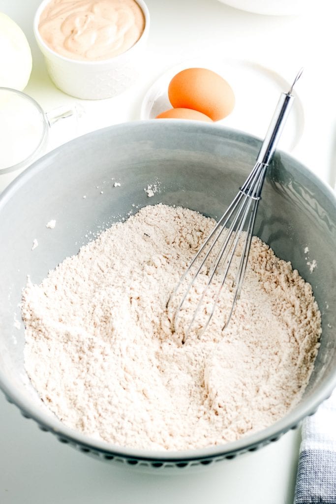 Gray bowl with flour and spices whisked together for batter.
