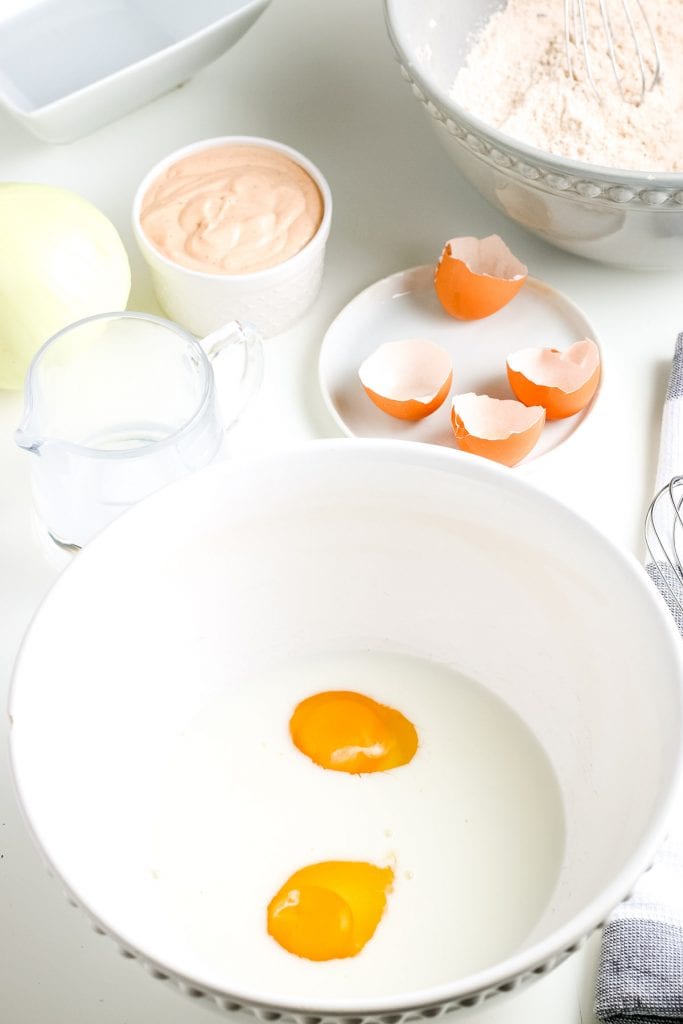 Eggs and milk in white bowl before whisking together. 