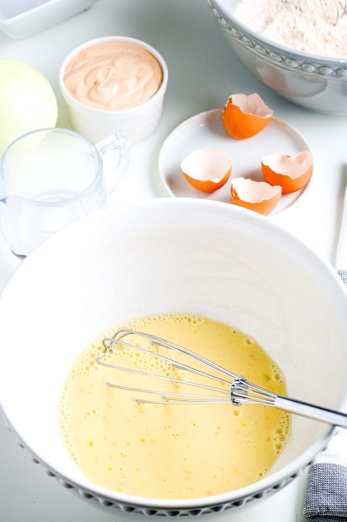 Whisked eggs in bowl with a whisk sitting in the bowl.