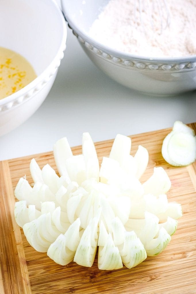 Onion cut to look like it's blooming on wooden cutting board.