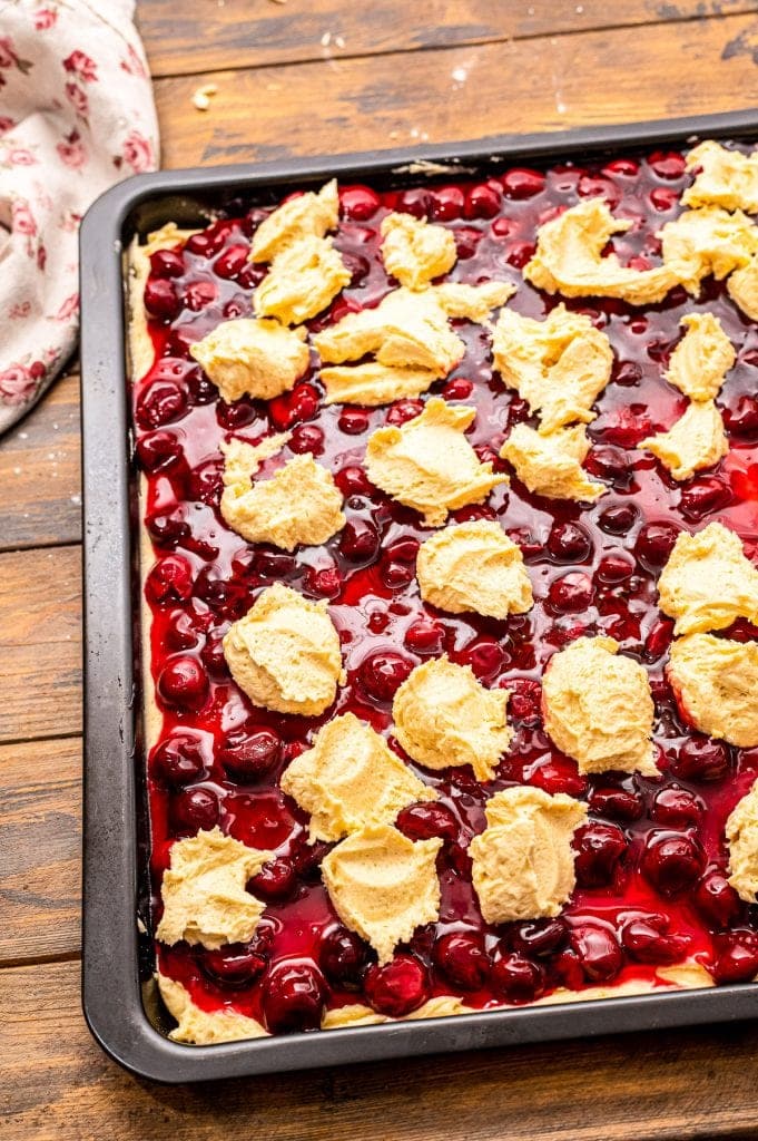 Dropping batter on top of cherry pie filling in pan for bars