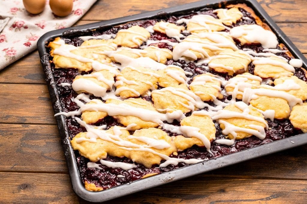 Pan of prepared cherry pie bars drizzled with icing.