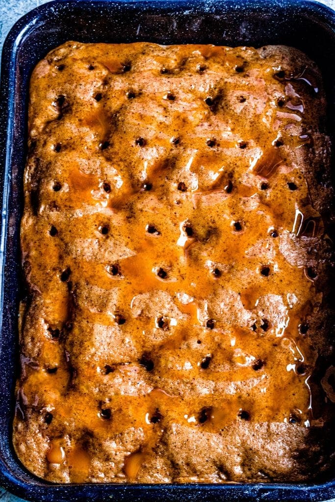 Dulce de Leche Apple Poke Cake with holes poked in it and dulce de leche drizzled over it.