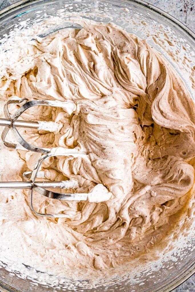 Dulce de Leche Apple Poke Cake whipped cream that's prepared in glass bowl with hand mixer