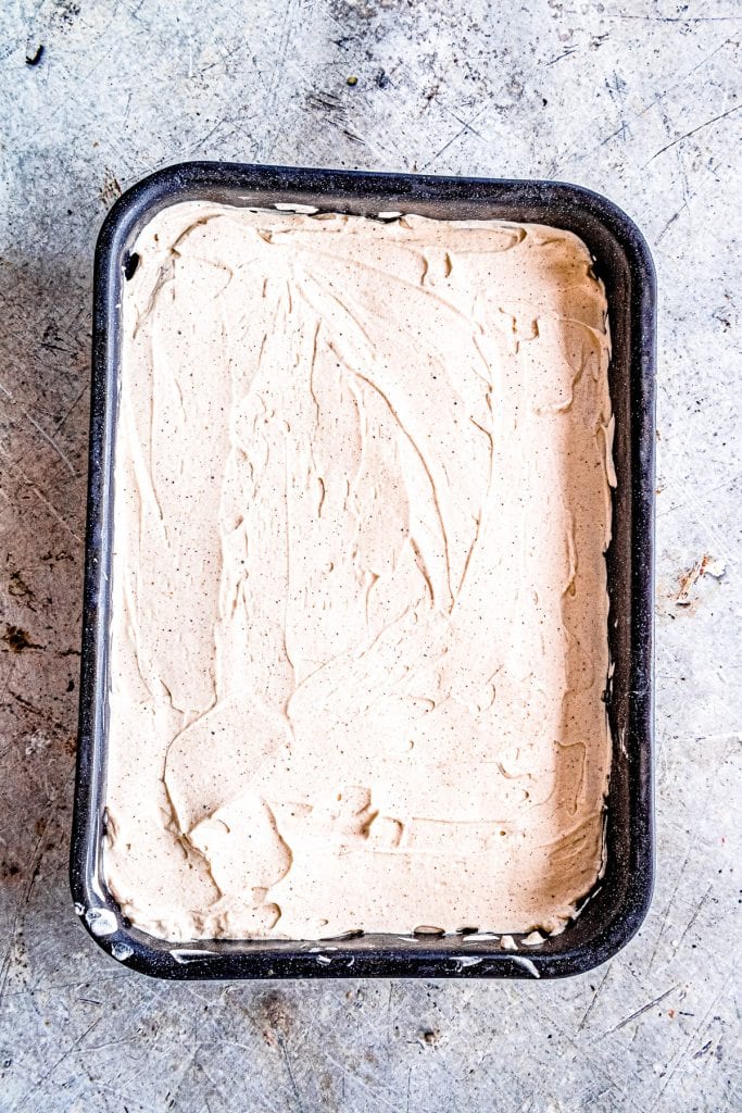 Dulce de Leche Apple Poke Cake with frosting in cake pan