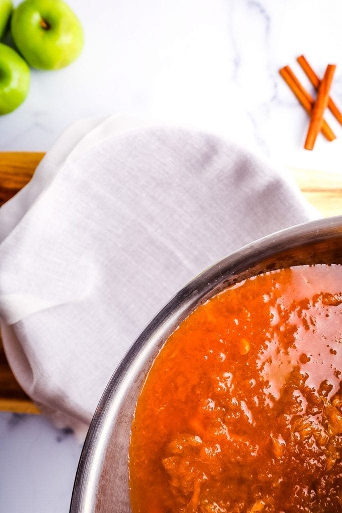 Apple Cider being poured out of Instant Pot into cheesecloth to drain it.