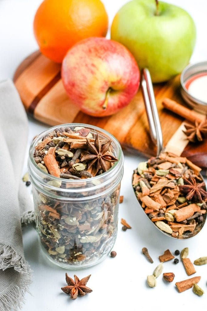 Mulling Spices in glass jar with apples behind it.