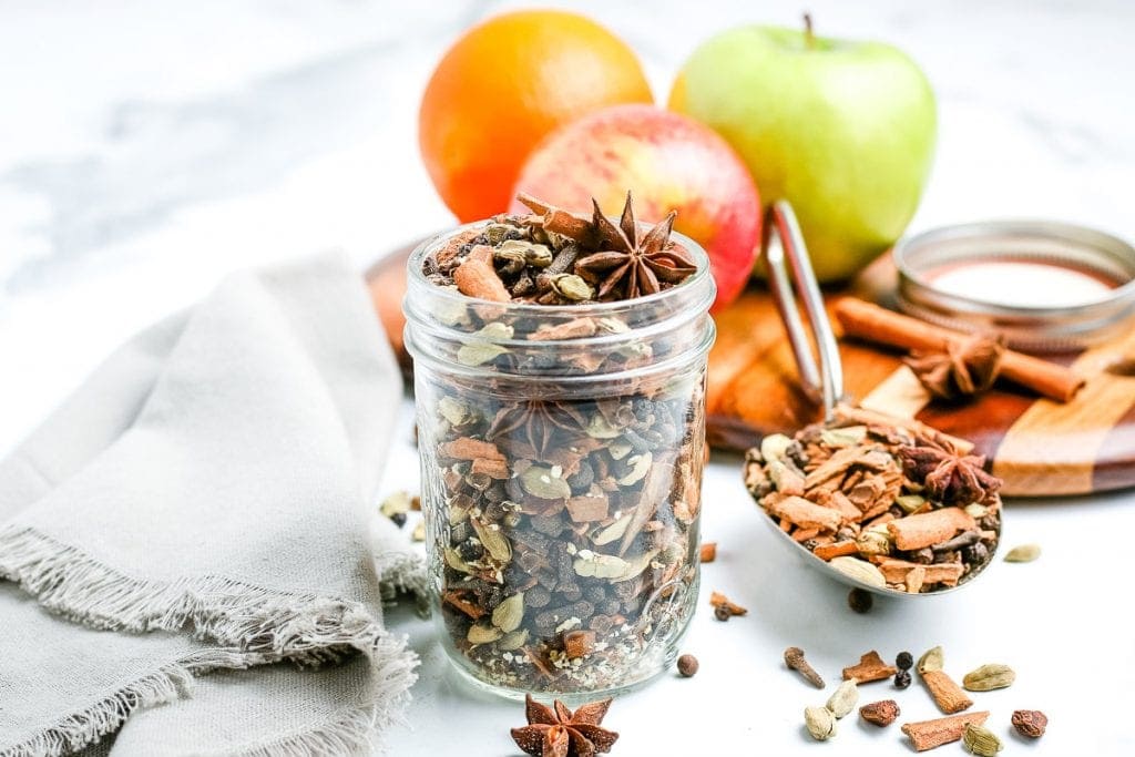 Mulling Spices in glass jar with apples, spices, and napkin background.