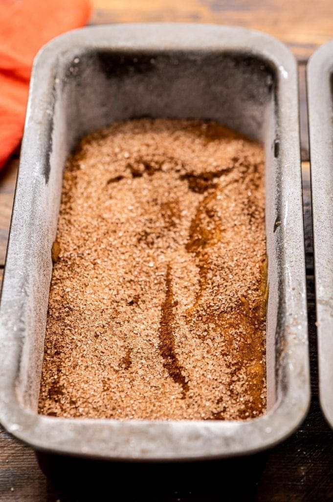 Metal loaf pan with pumpkin zucchini bread in it and cinnamon sugar on it.