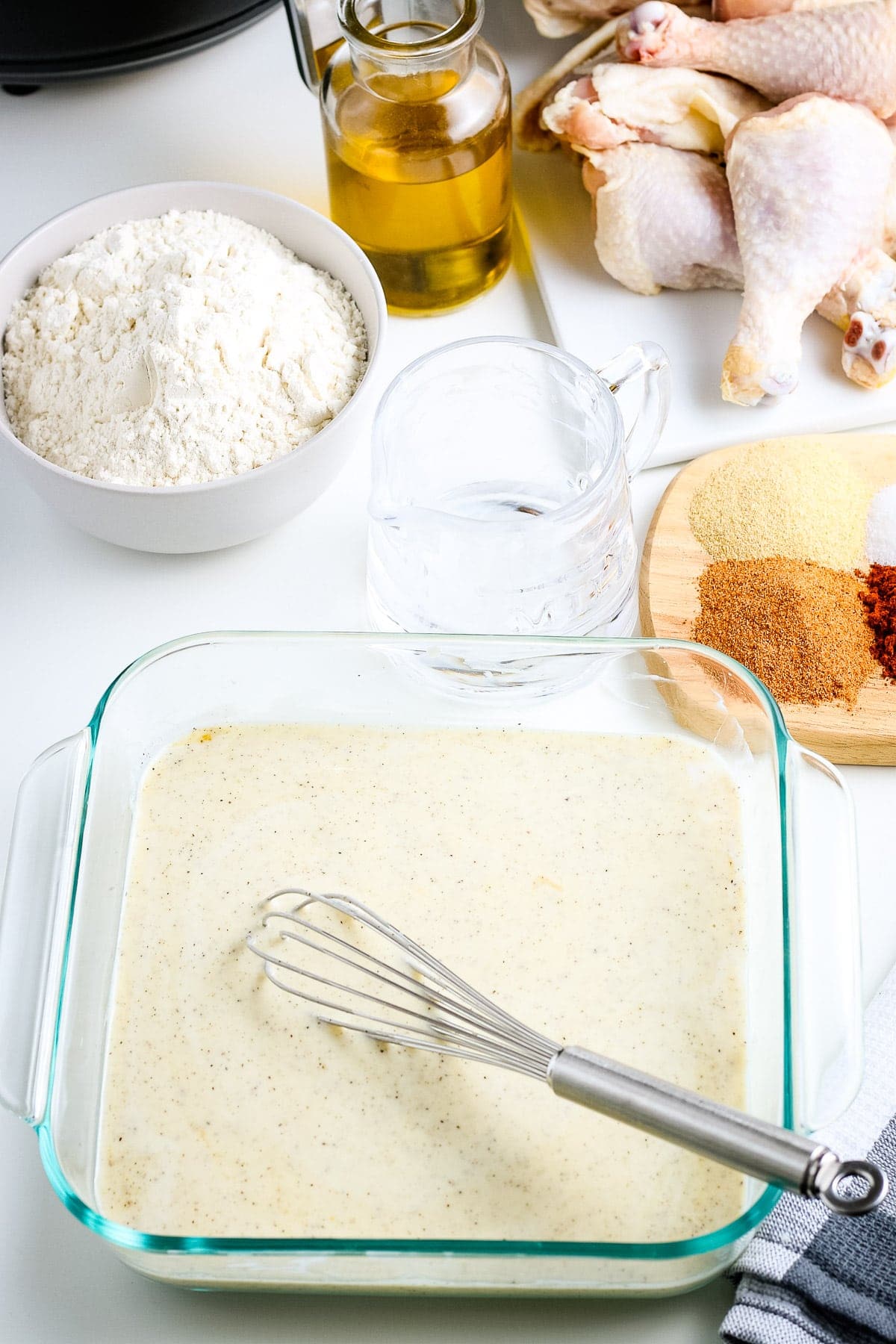 Buttermilk batter whisked together in square clear dish with whisk in dish.