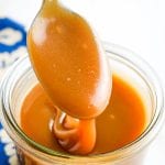 Caramel Sauce on spoon drizzling into jar of sauce.