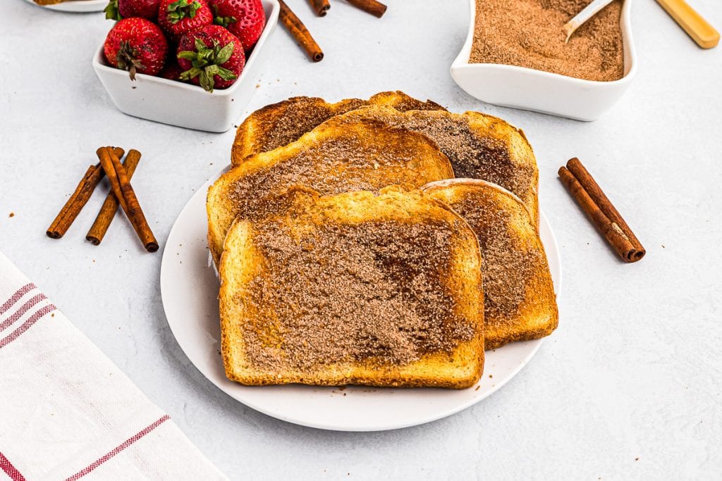 Buttered toast with cinnamon sugar on it stacked on plate.