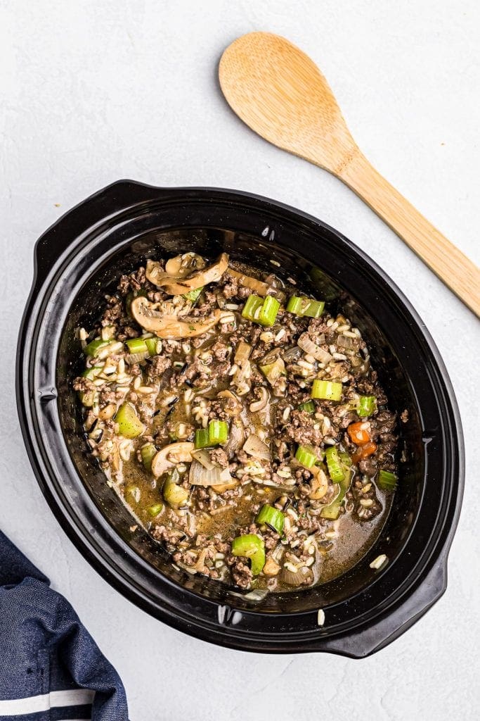 Crock pot with ingredients in it to make Crock Pot Hamburger Wild Rice Casserole after stirring.