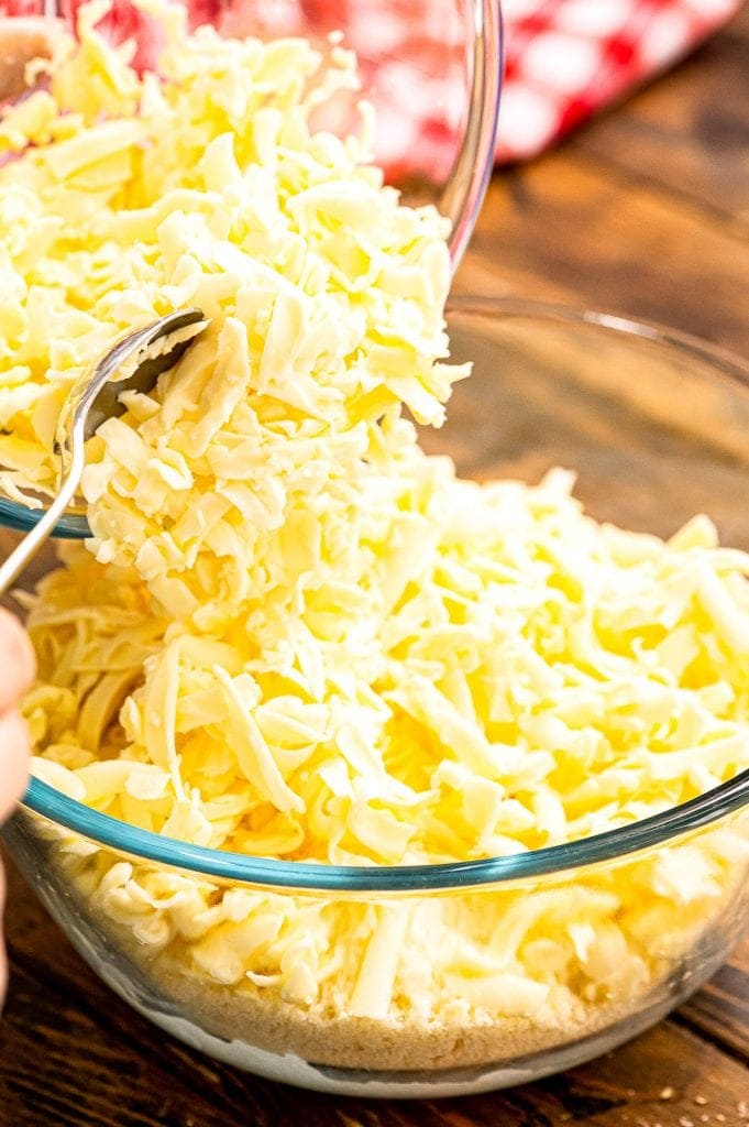 Spooning shredded Mozzarella into glass bowl.