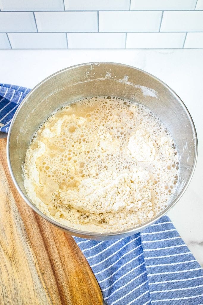 Metal bowl with yeast mixture added to flour mixture.