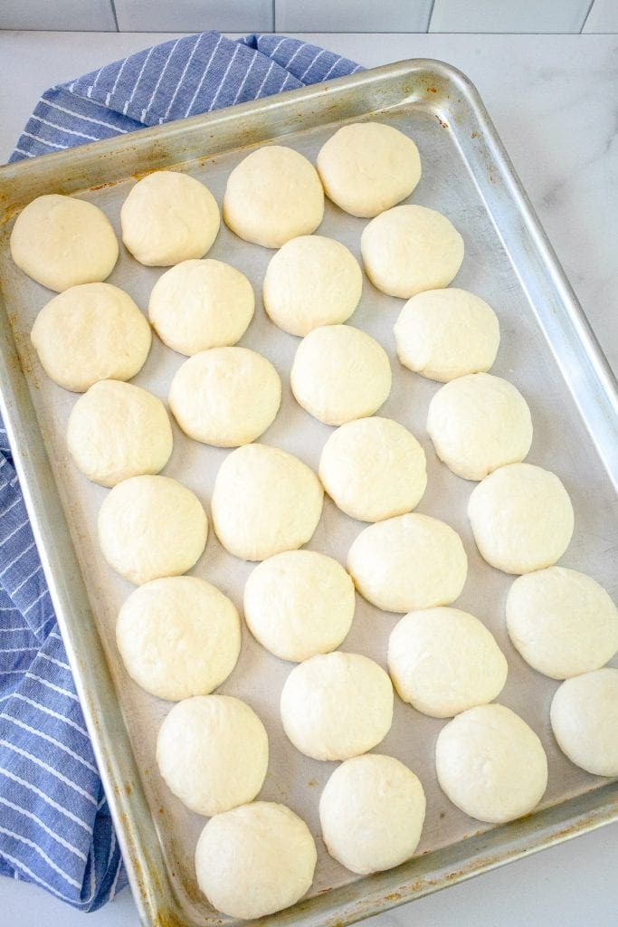 Baking sheet with dinner rolls dough balls on it.