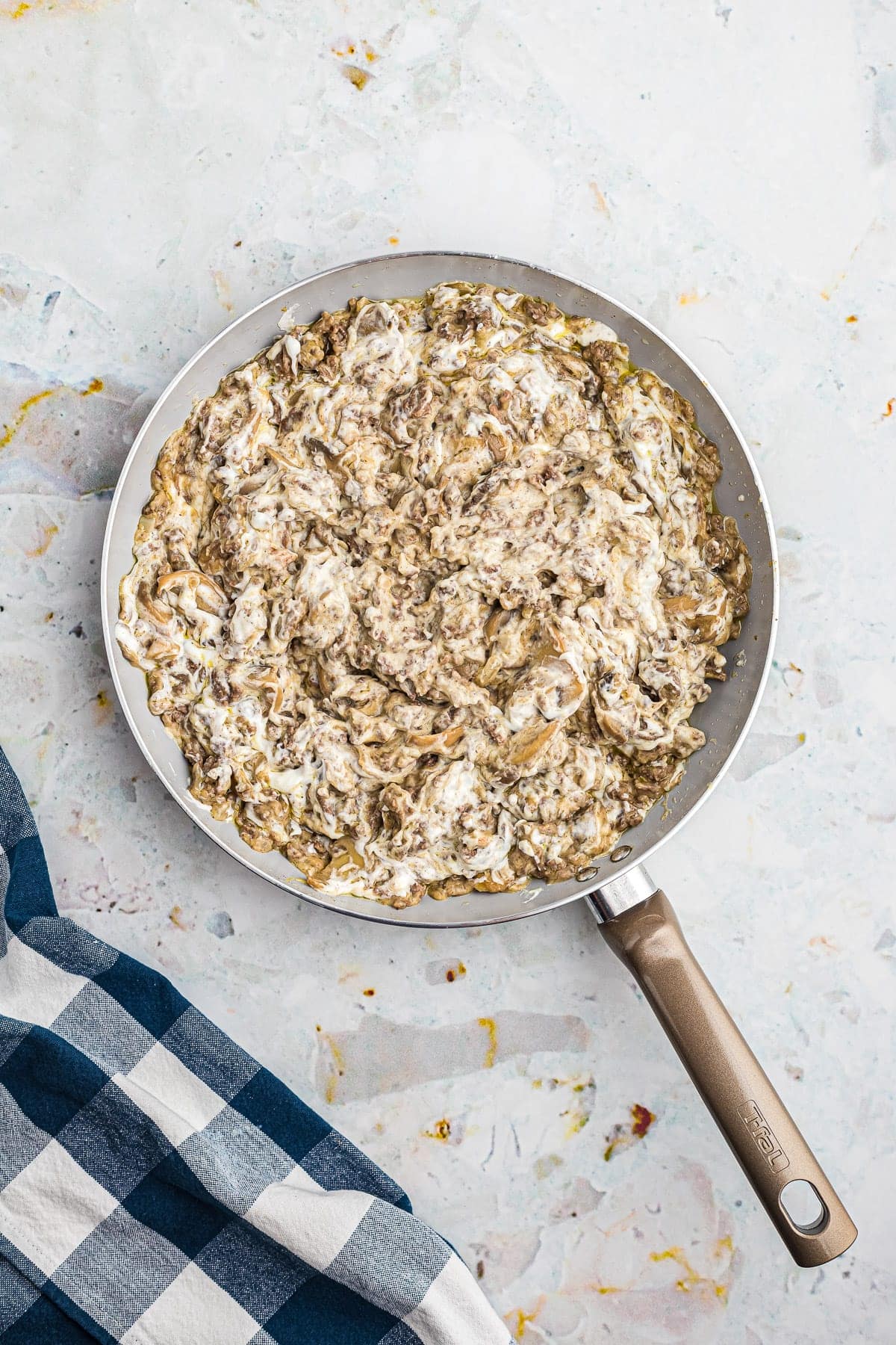 Hamburger Stroganoff in skillet with blue napkin next to it.