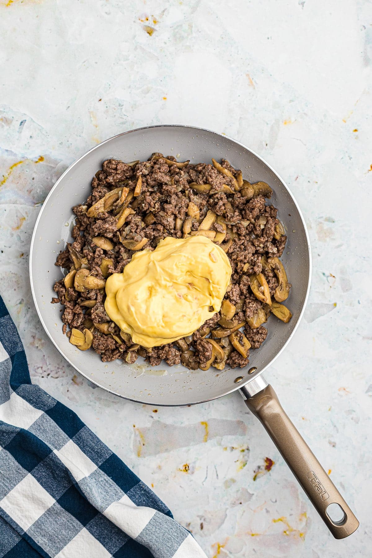 Skillet with meat mixture and cream of chicken soup on top before mixing.