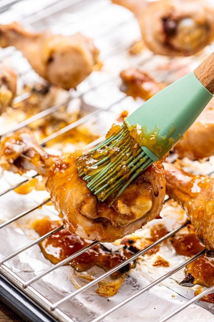Chicken leg being brushed with honey garlic sauce