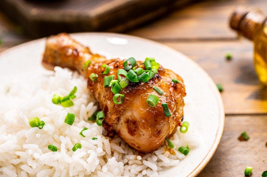Honey Garlic Chicken Leg on white plate with white rice next to it.