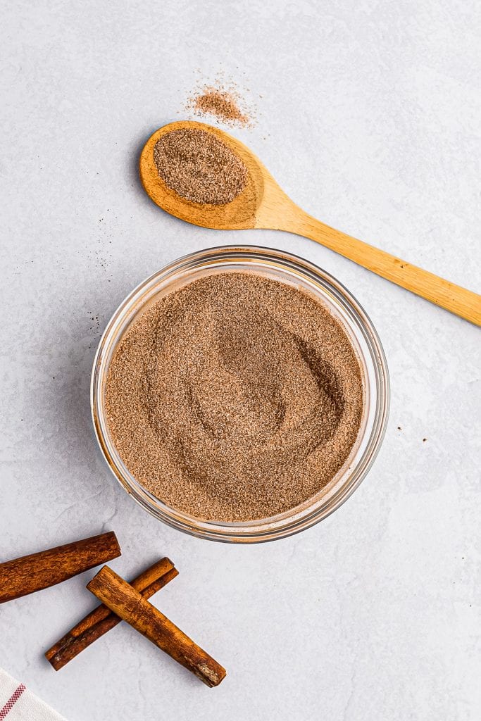 Glass bowl with cinnamon and sugar in it after stirring.