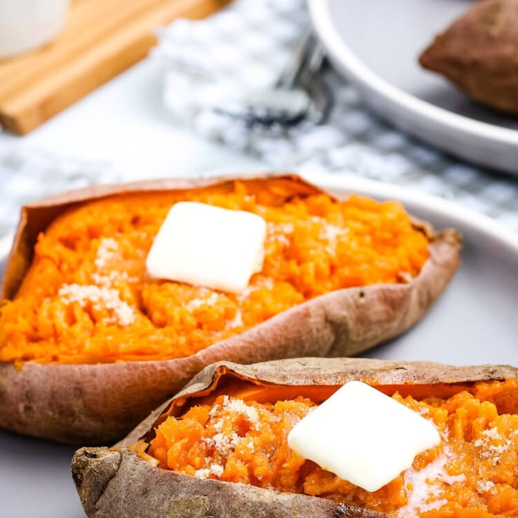 White Plate with two sweet potatoes with a slab of butter on top of each one.