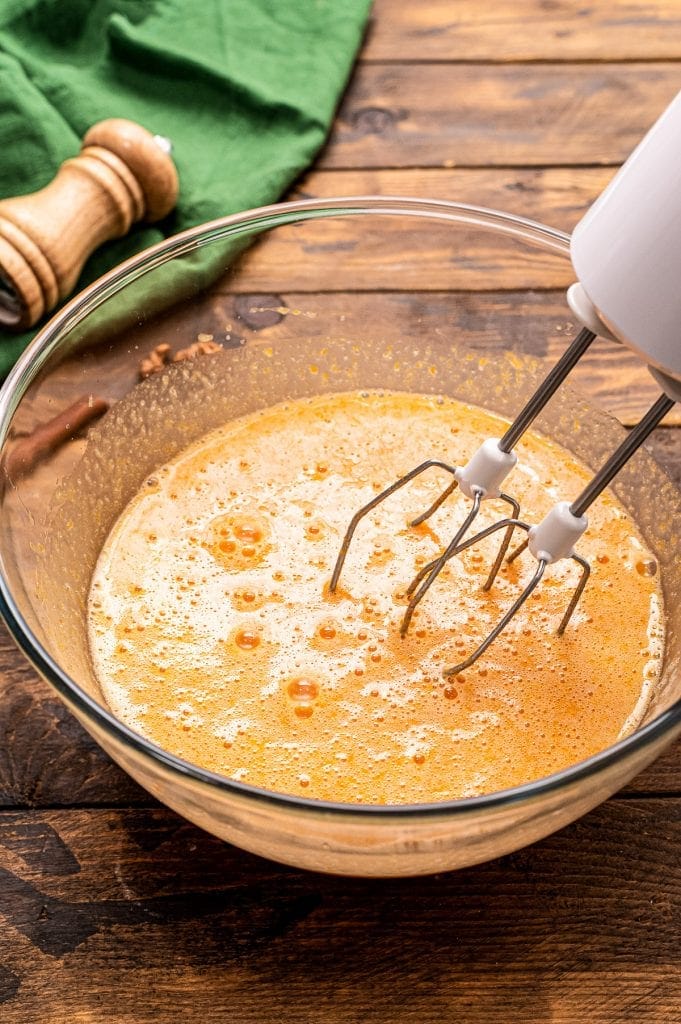 Hand mixer mixing wet ingredients for pumpkin batter