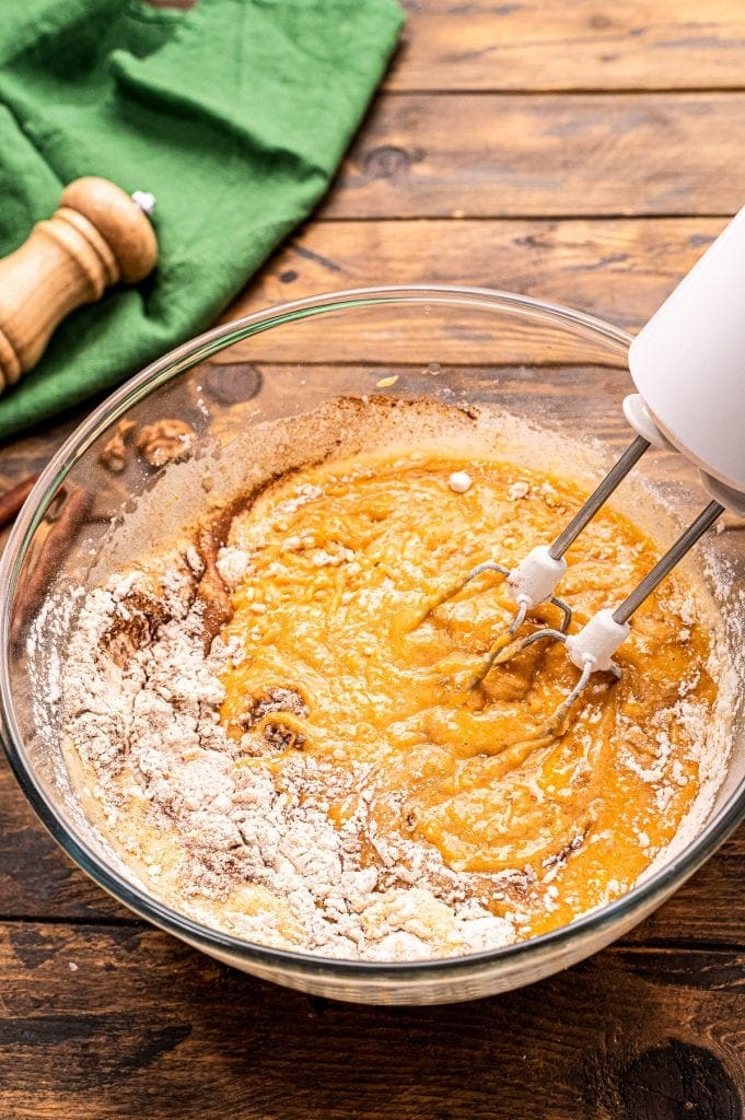 Hand mixer combine dry and wet ingredients in glass bowl for pumpkin bars