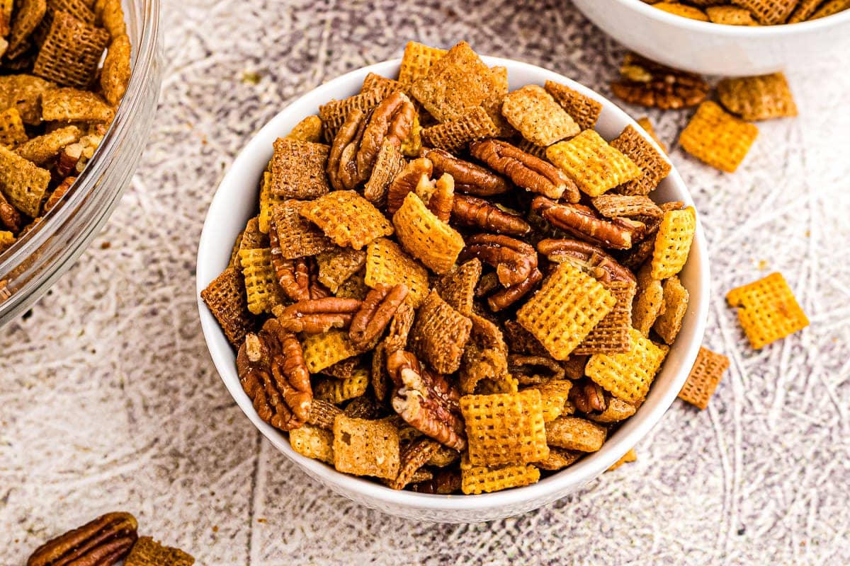 Overhead image of white bowl with pumpkin chex mix in it