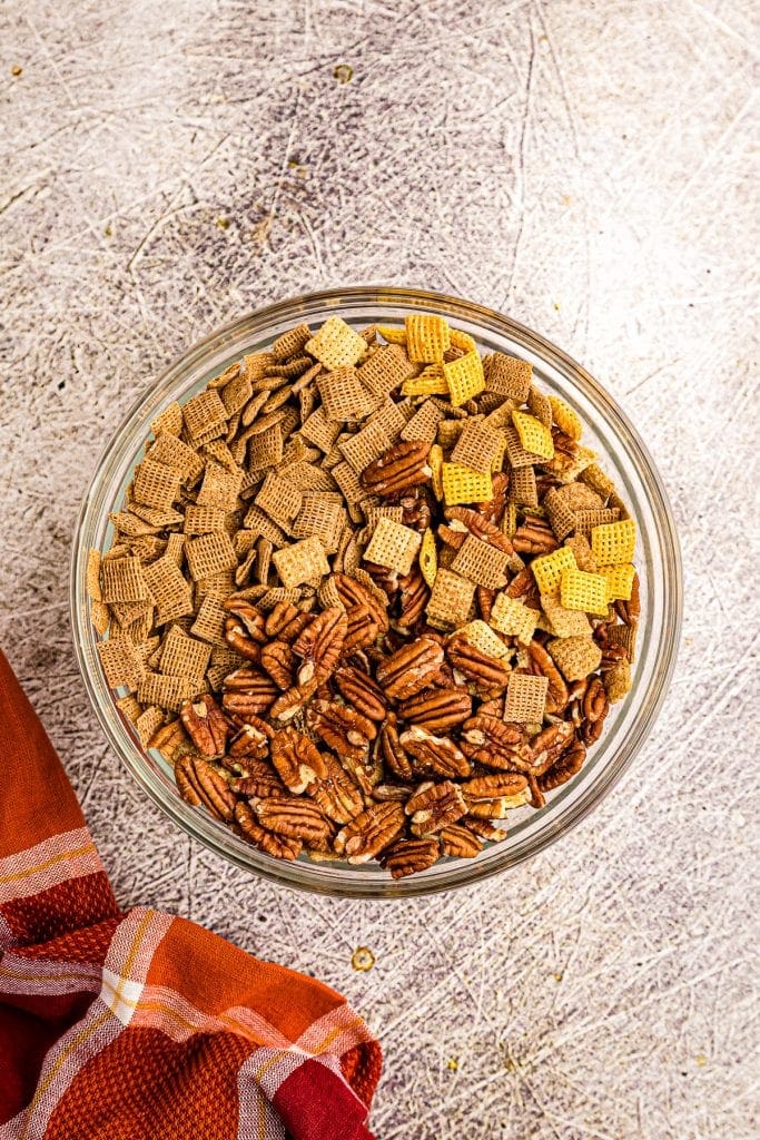 Glass bowl with chex cereals and pecans before stirring.