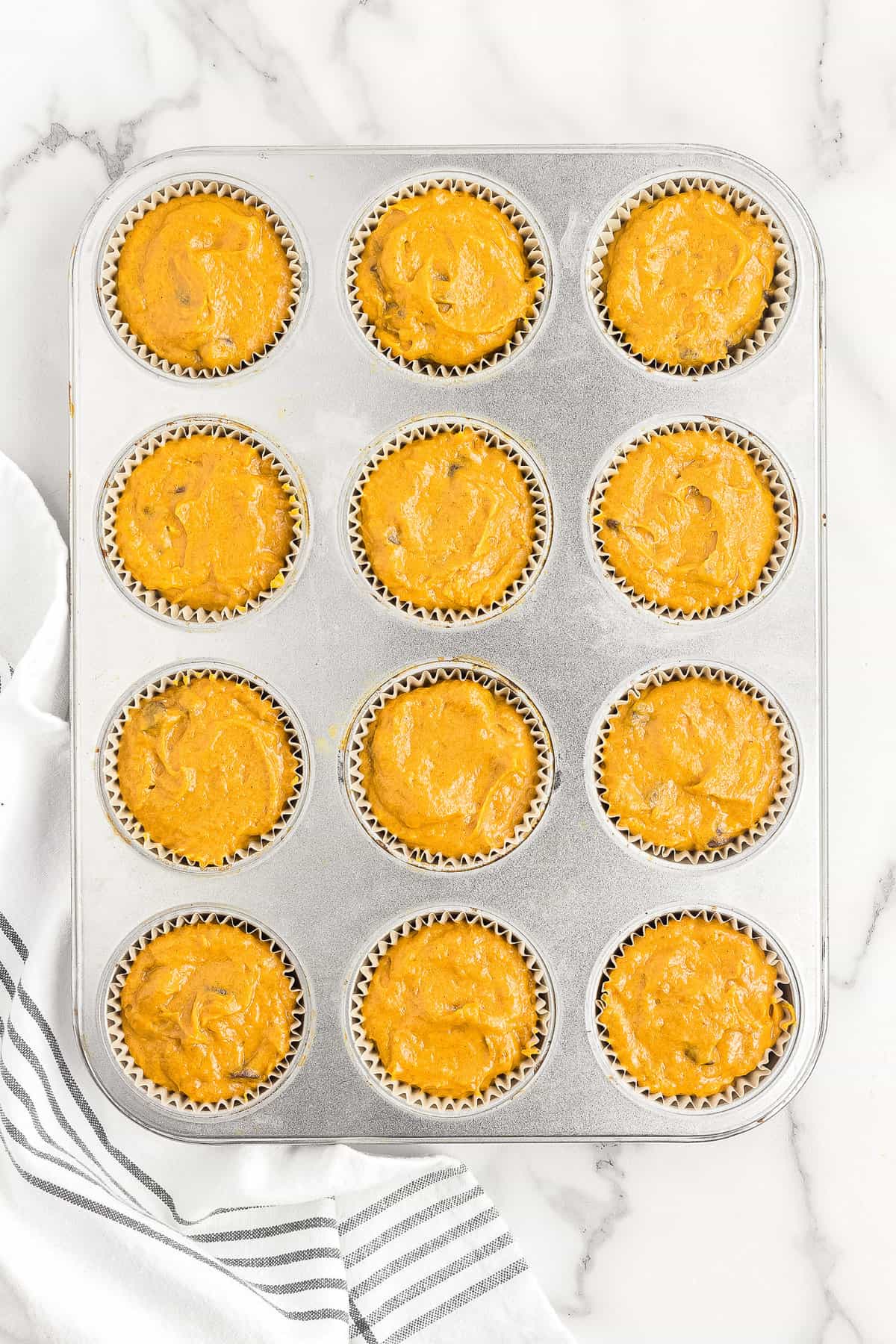 Muffin tin with chocolate chip pumpkin muffin batter