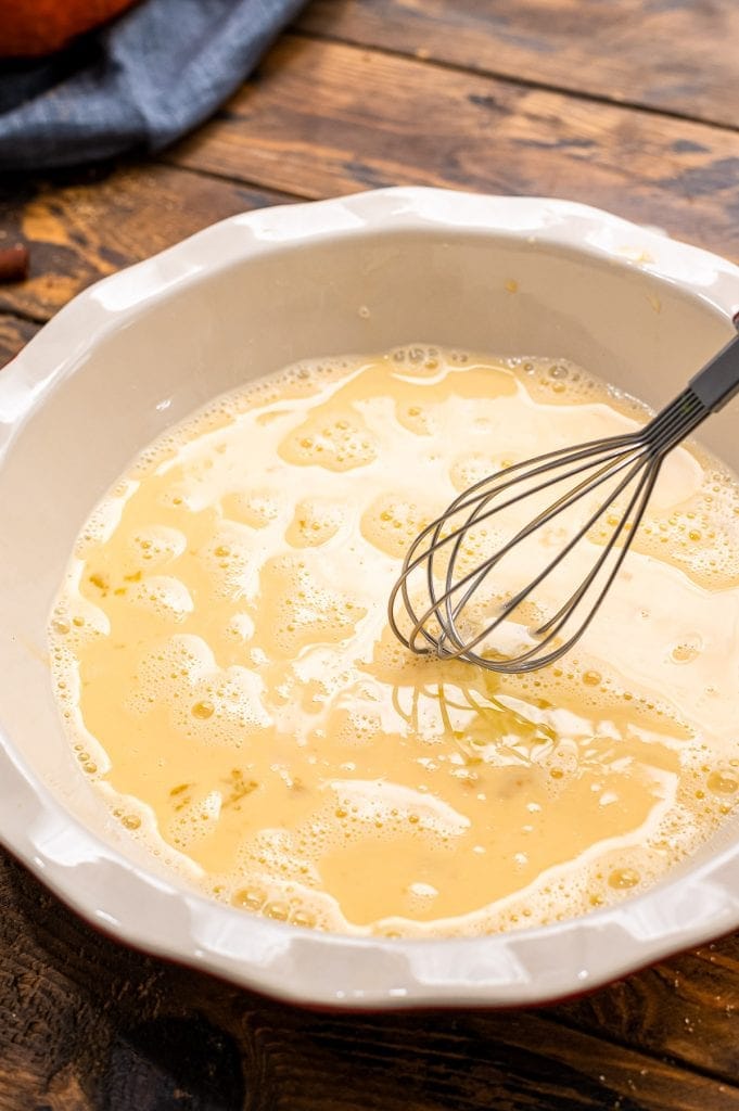 A white pie plate with french toast batter after whisking.