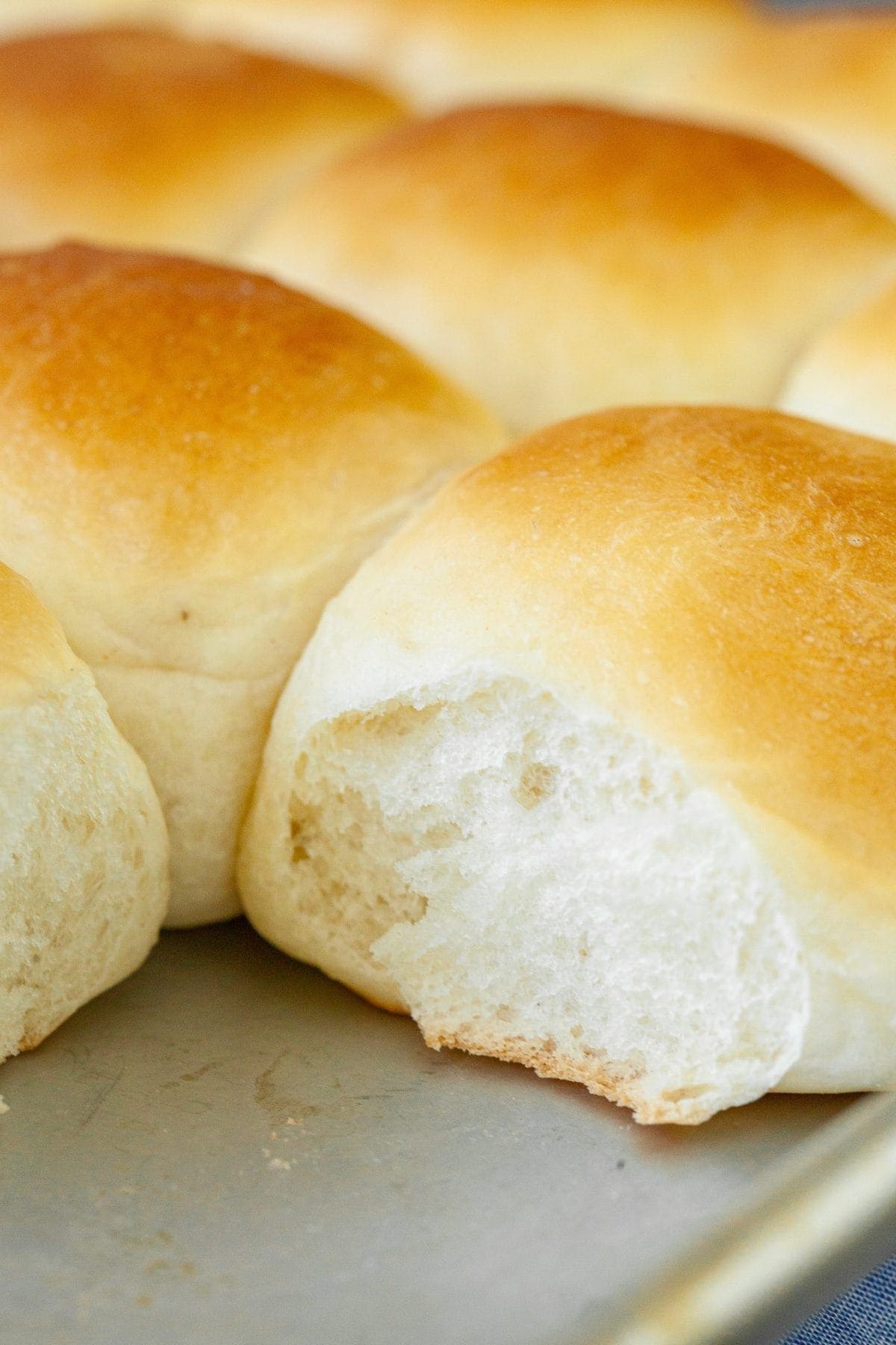 Close up of dinner rolls on baking pan with the corner one missing.