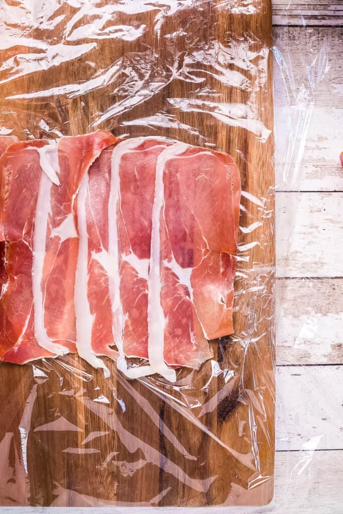 Prosciutto laid out on plastic wrap