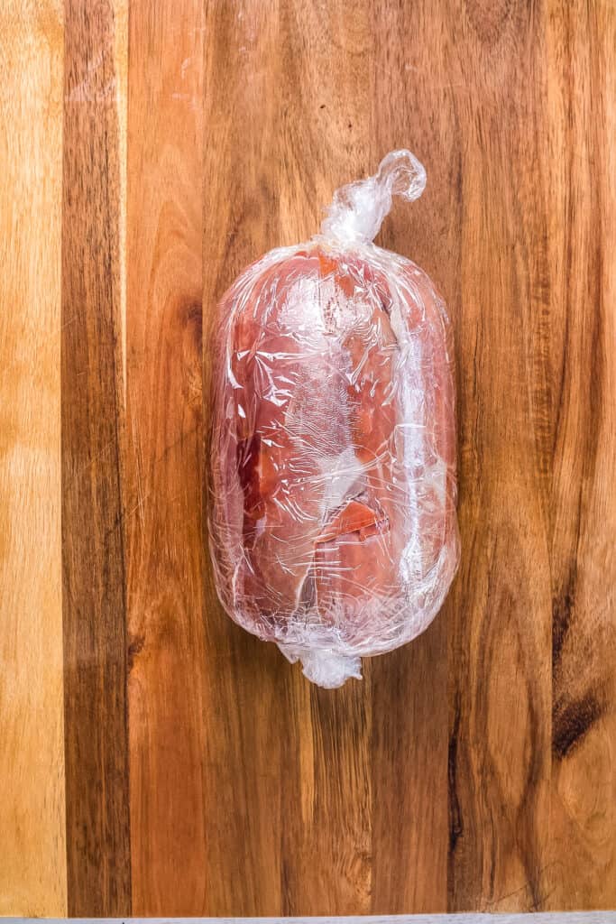 Prosciutto wrapped beef tenderloin wrapped in plastic wrap