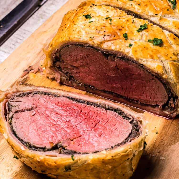 Slice of Beef Wellington on wooden cutting board