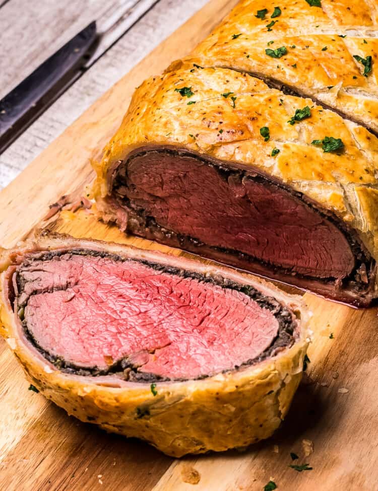 Slice of Beef Wellington on wooden cutting board