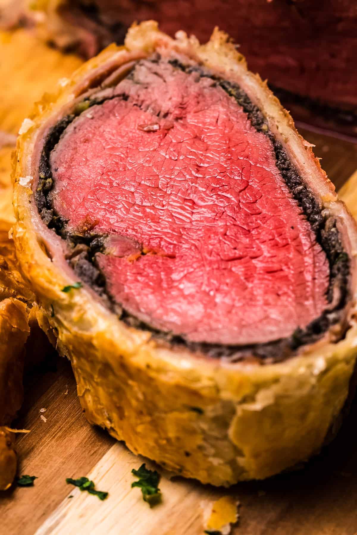 Slice of beef wellington sitting face up on cutting board