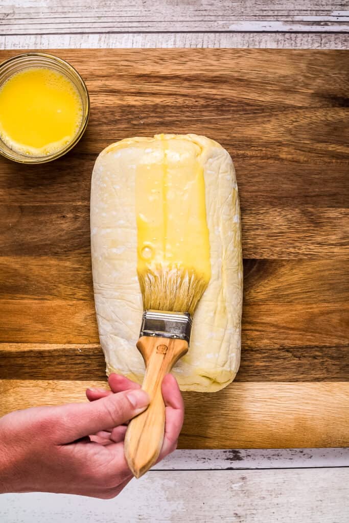 Hand brushing butter on puff pastry with pastry brush